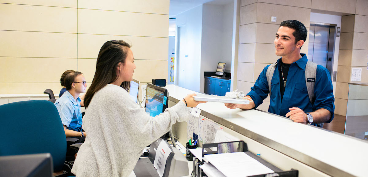 Student handing book at Circulation Desk