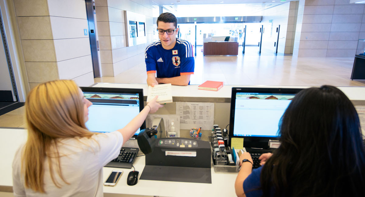 Student handing book over at Circulation Desk